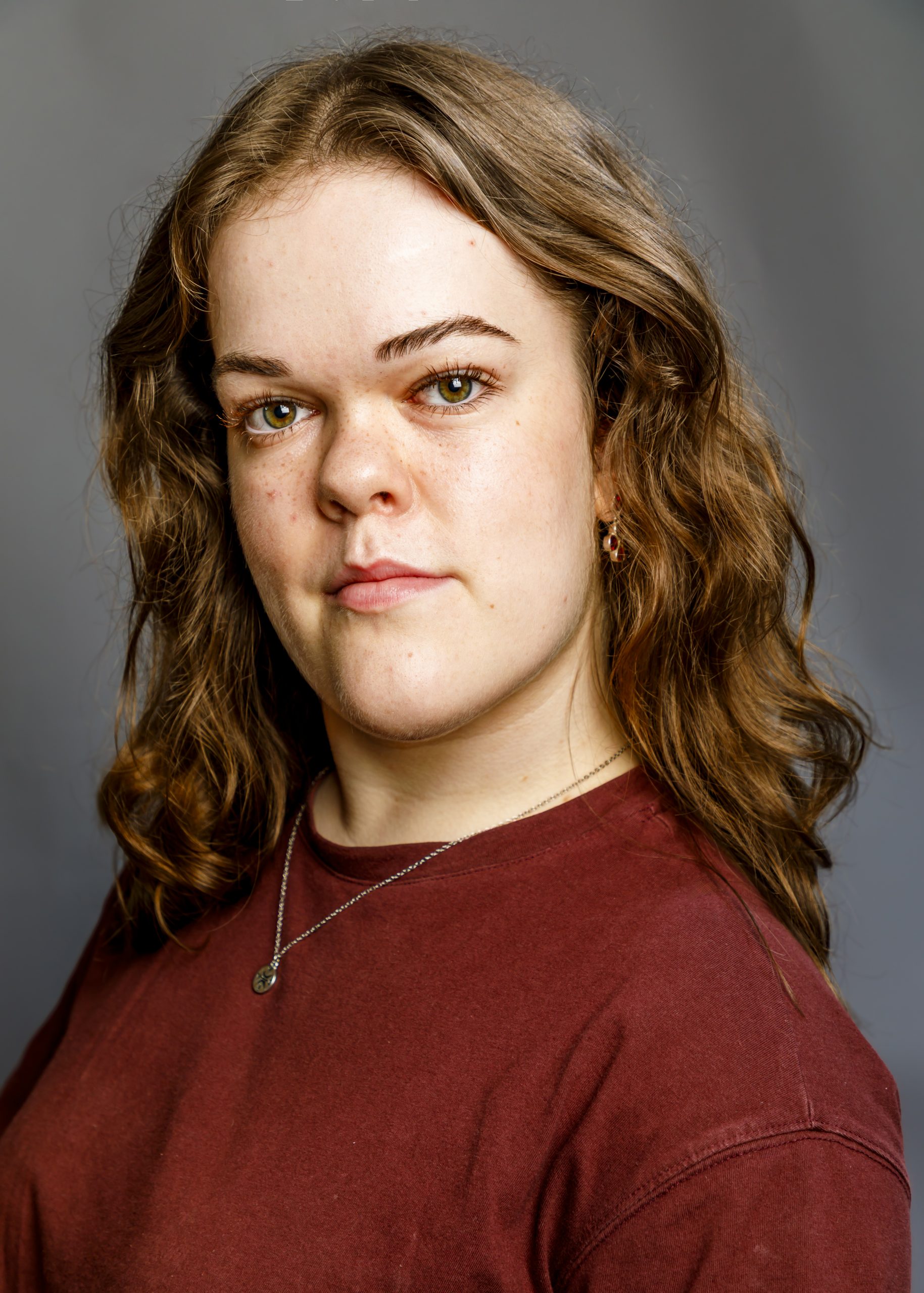 Professional headshot of a woman with wavy hair against a light grey background, taken by Marcos Appelt Portrait Photographer in Bristol and Southwest.