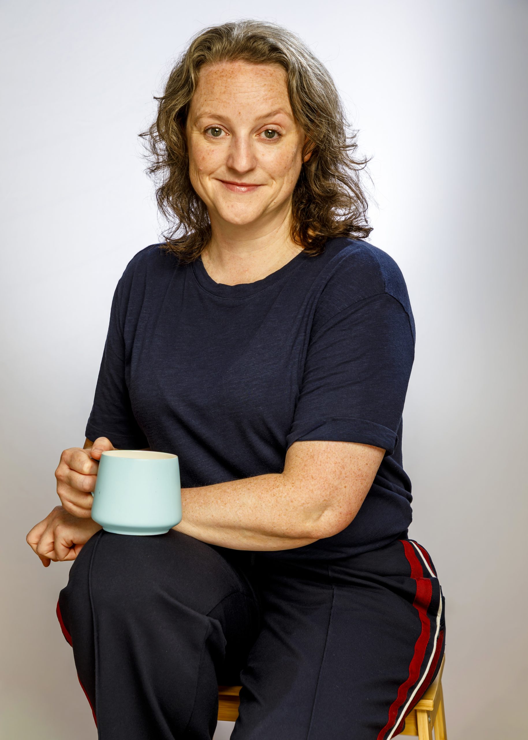 Professional portrait of a woman in a red dress against a glowing orange background, taken by Marcos Appelt Portrait Photographer in Bristol and Southwest.”