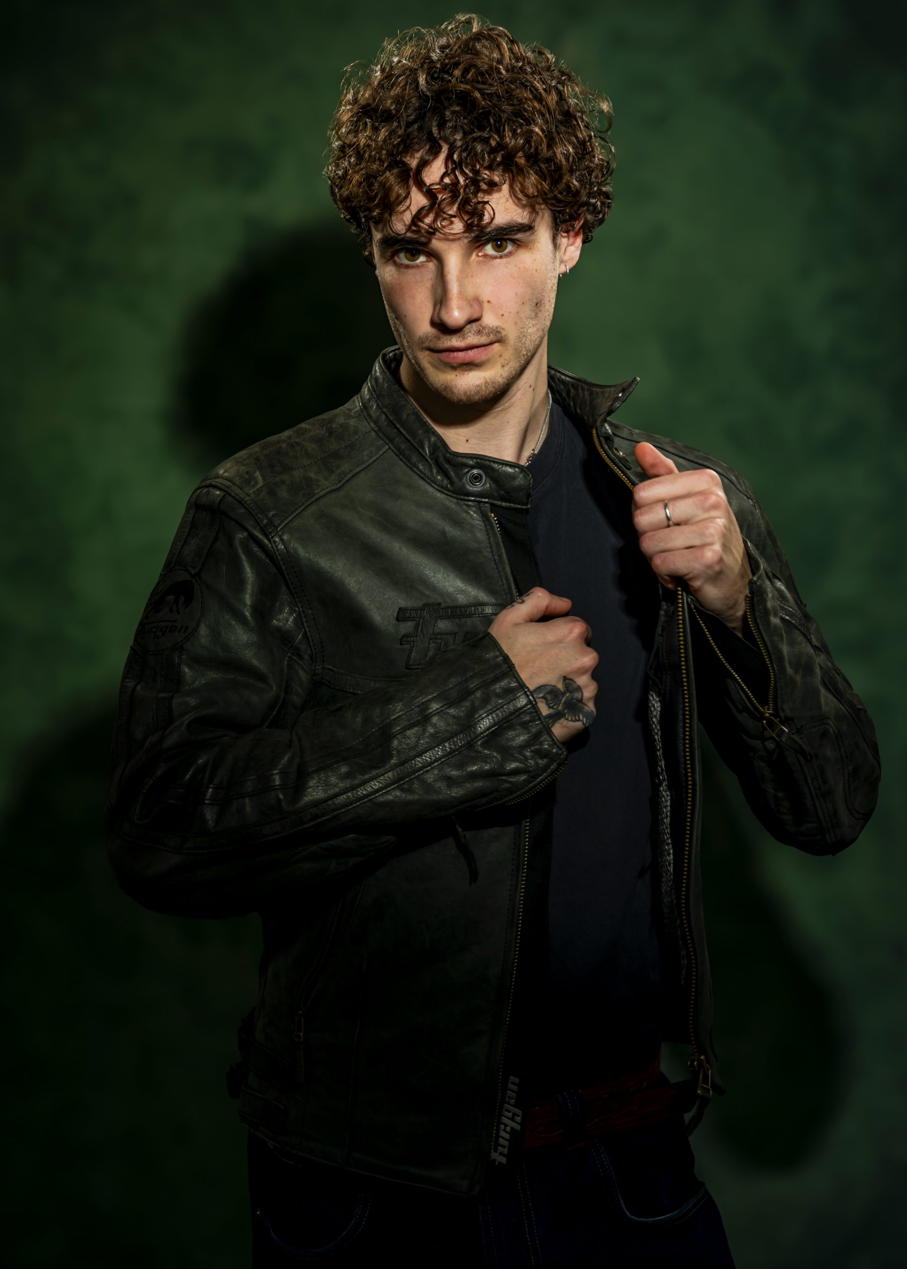 Professional portrait of a man in a dark jacket against a textured green background, taken by Marcos Appelt Portrait Photographer in Bristol and Southwest.